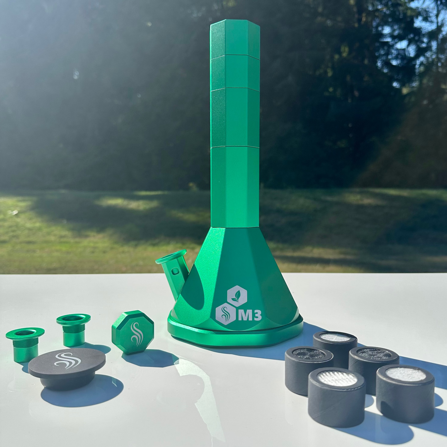 Green M3 Pro Bong with various components on a white surface outdoors