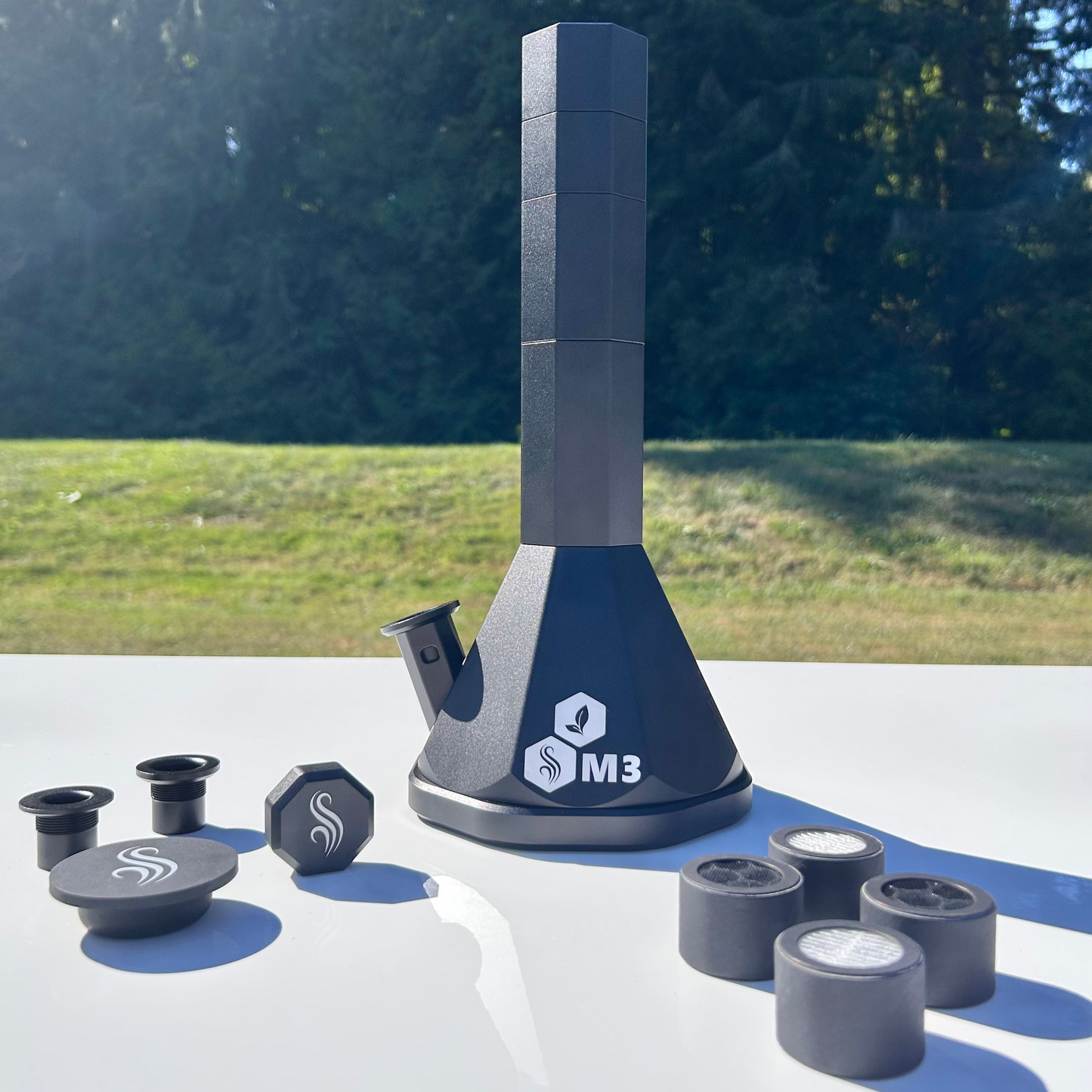 Black M3 Pro Bong with accessories and 4 M2/M3 M Series filters on a white surface outdoors