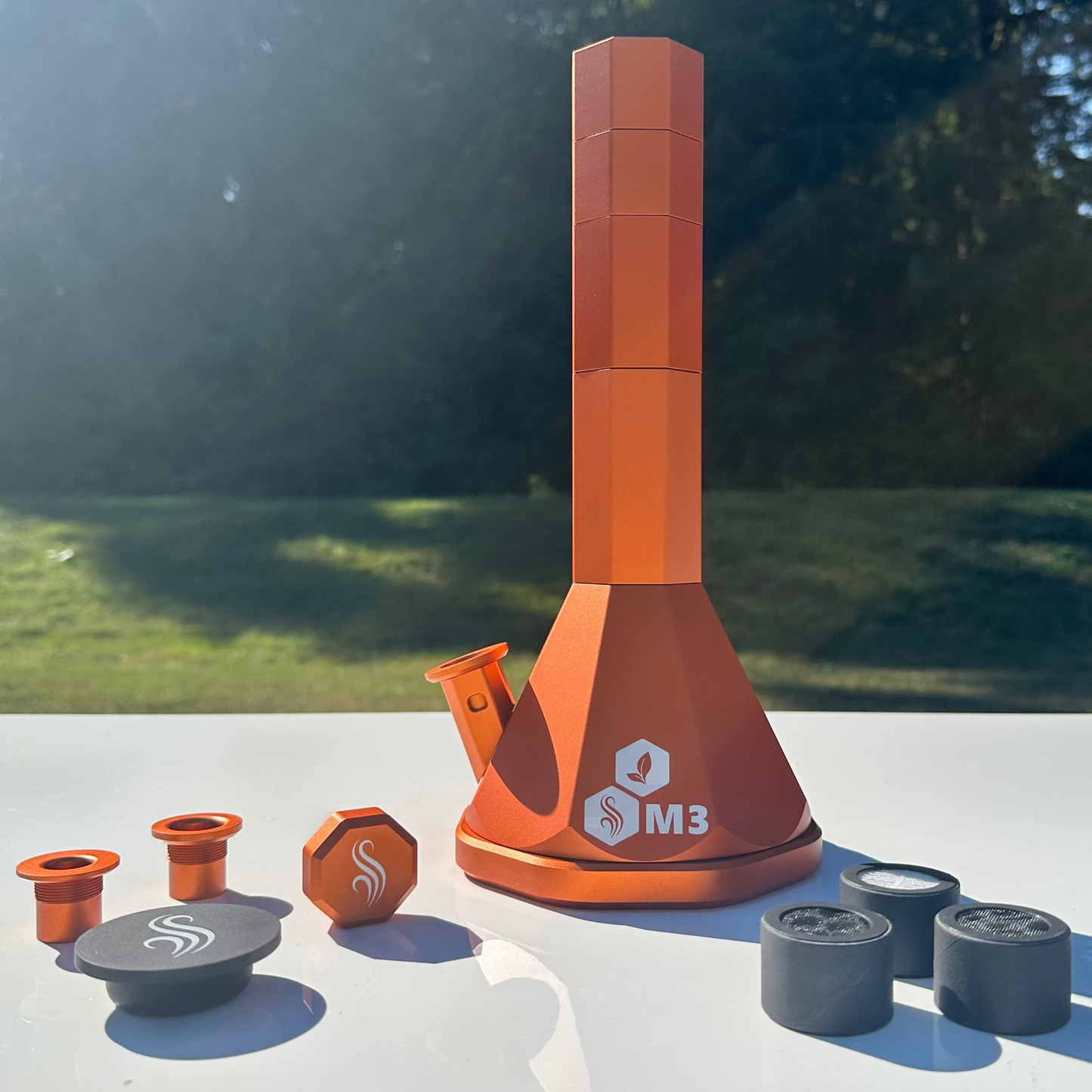 Orange M3 Pro Bong with accessories and 3 M2 M3 M Series Filters on a white surface outdoors