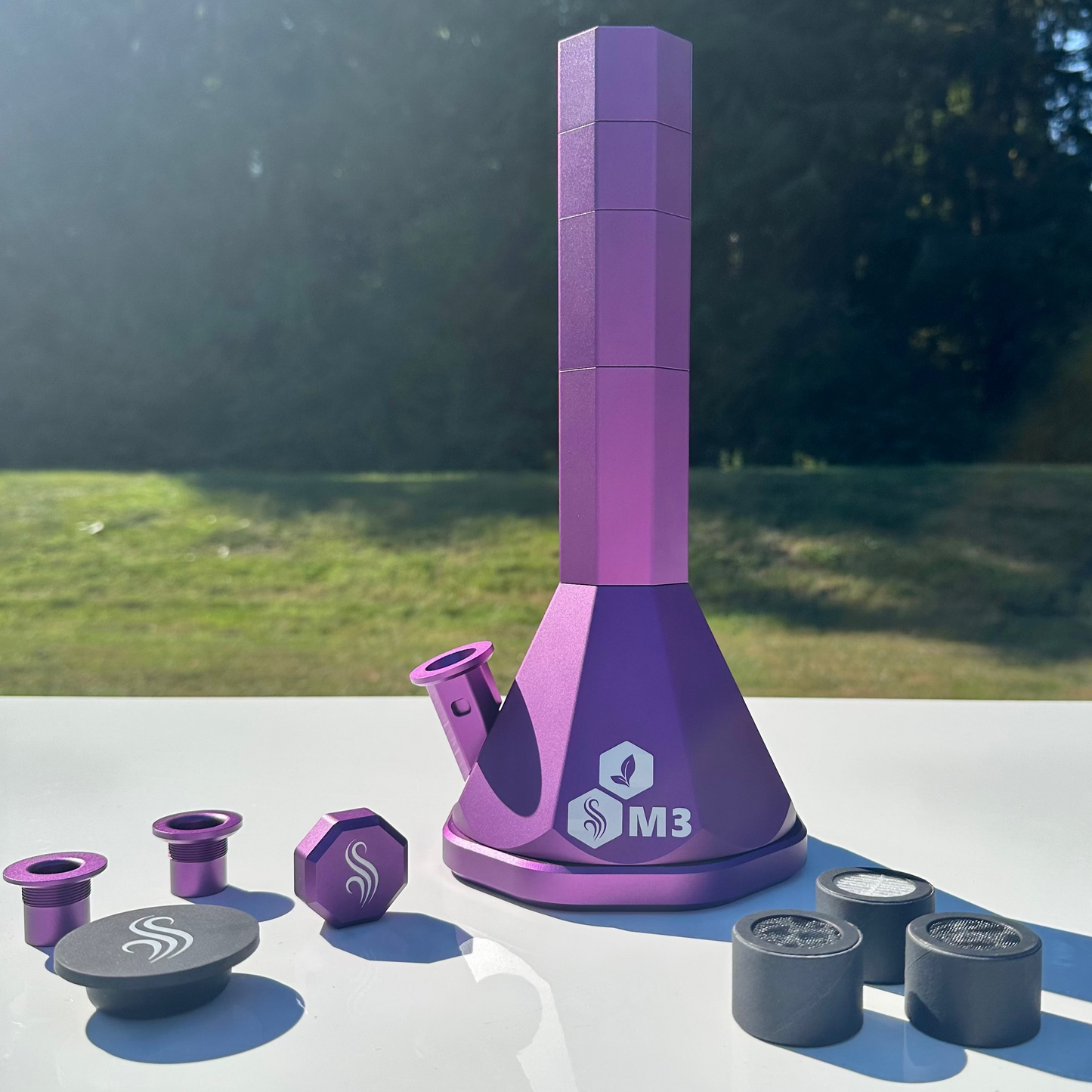 Purple M3 Pro Bong with accessories and 3 M Series filters on a white surface outdoors