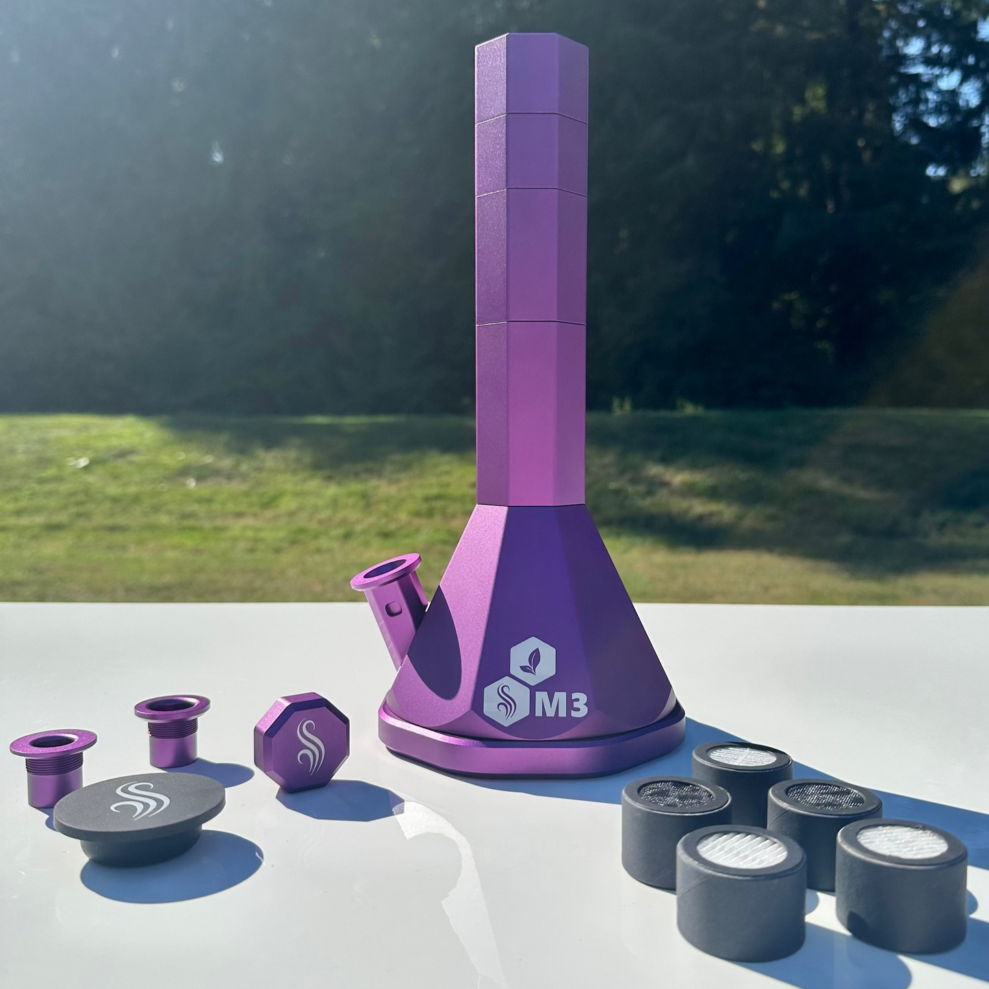 Purple M3 Pro bong with accessories and 5 M2/M3 M Series filters on a white surface outdoors